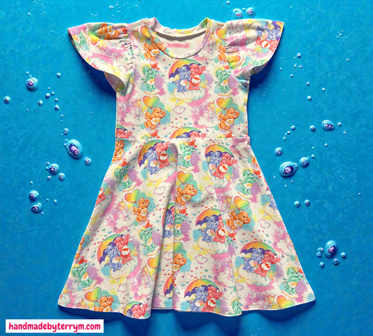 Girls dress with Colourful carebears with hearts rainbows and clouds.